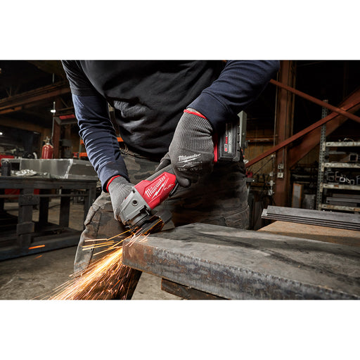 Person using a Milwaukee angle grinder on metal in an industrial setting